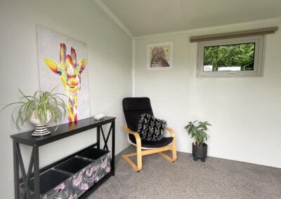 Cabin interior with side table, chair, plant and artwork on walls